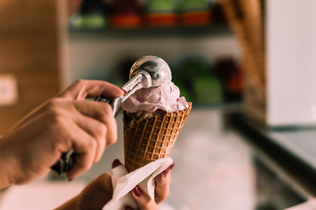 A person scooping ice cream into a cone in Norman, Oklahoma.