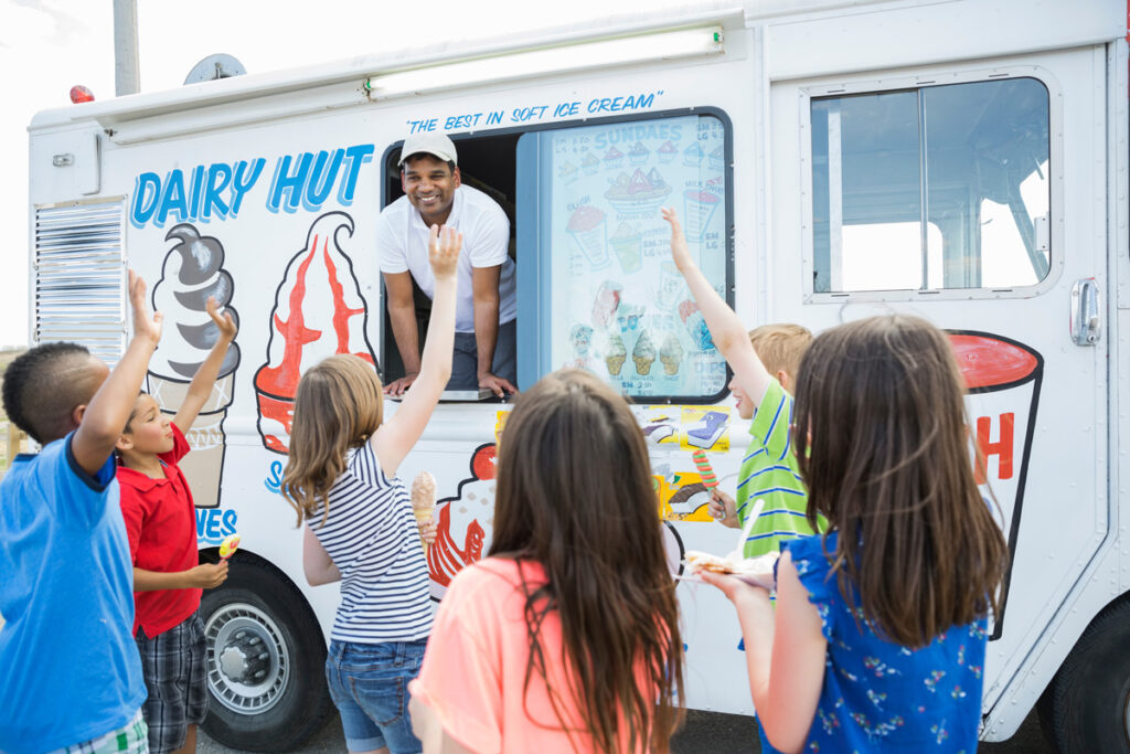 A man in an ice cream truck surrounded by excited children in Oklahoma.